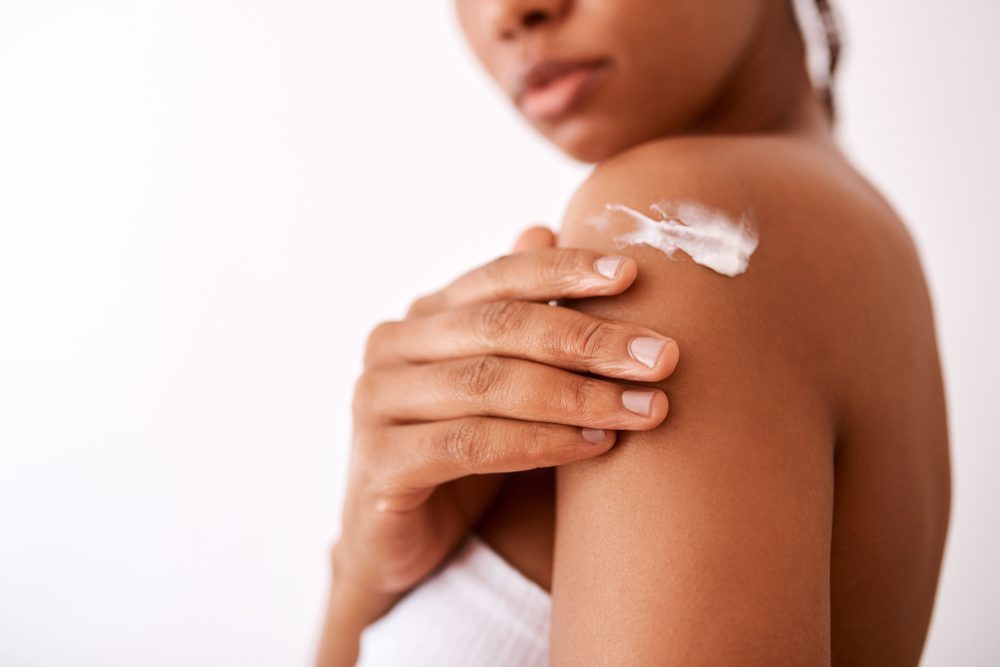 Woman rubbing moisturiser into her shoulder.