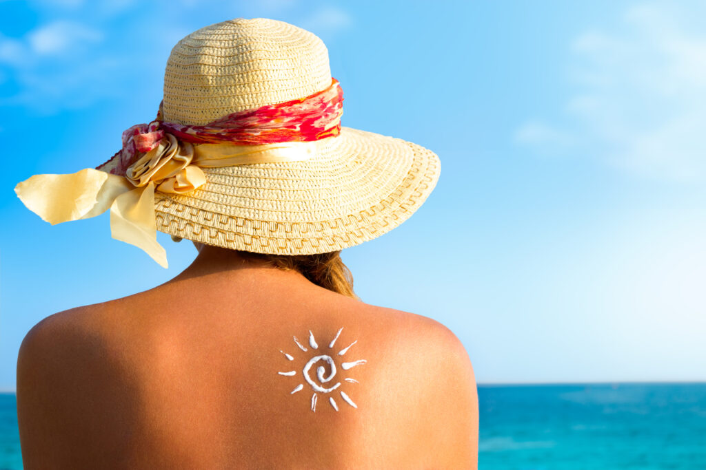 Woman looking out at the ocean with suncream on her back.